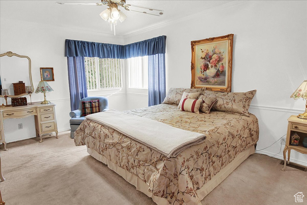 Carpeted bedroom with ceiling fan and crown molding
