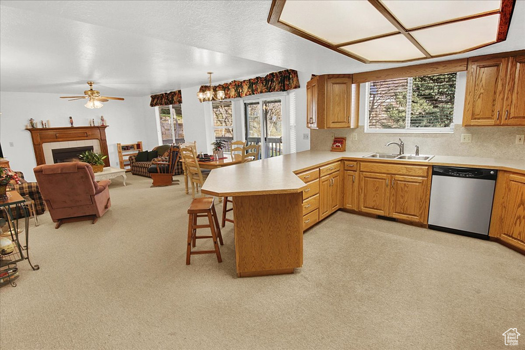 Kitchen featuring kitchen peninsula, sink, a breakfast bar area, light colored carpet, and dishwasher