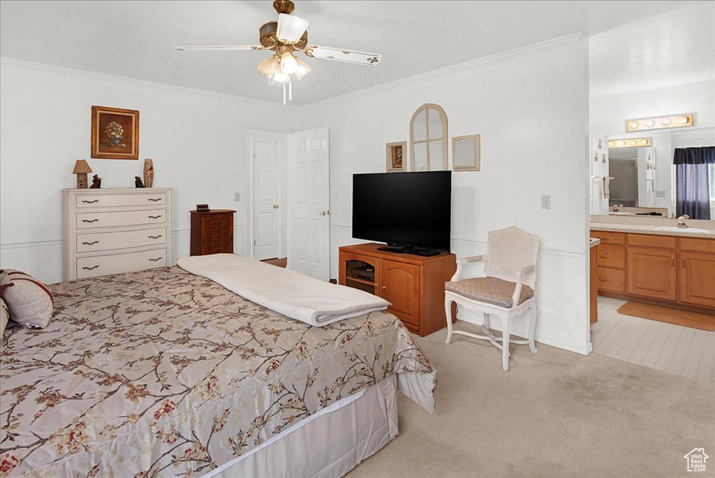 Bedroom featuring connected bathroom, ornamental molding, sink, light colored carpet, and ceiling fan