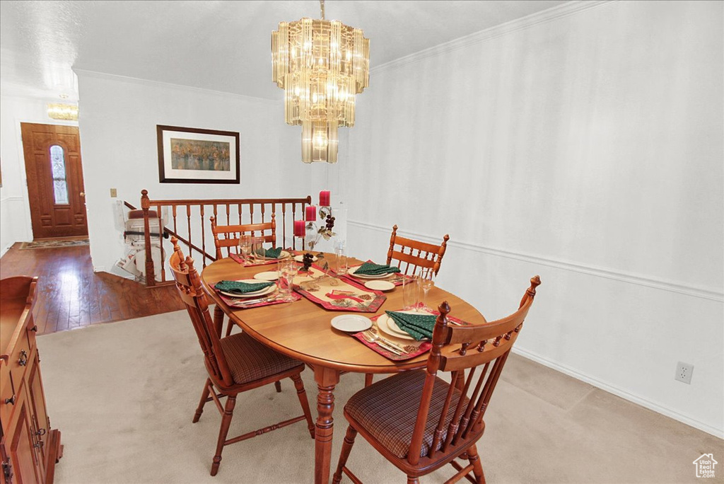 Dining room featuring wood-type flooring, an inviting chandelier, and ornamental molding