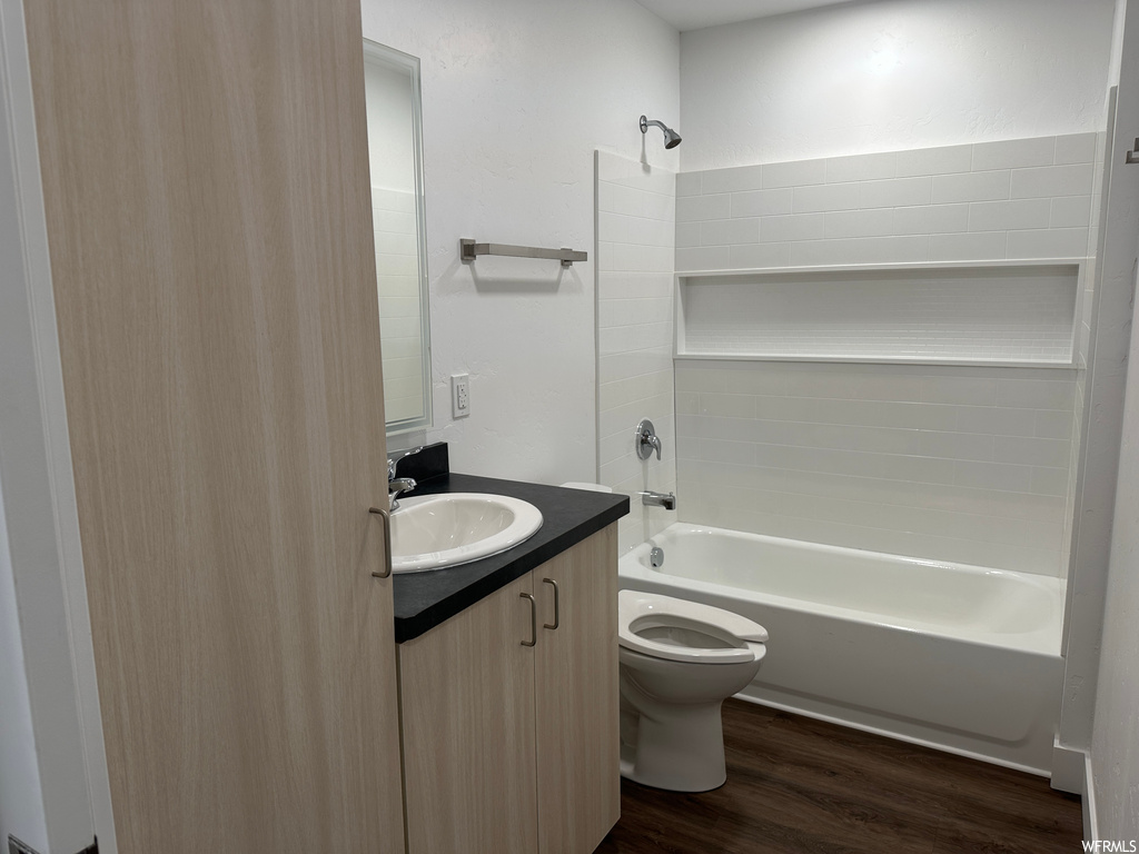 Full bathroom featuring toilet,  shower combination, vanity, and hardwood / wood-style floors
