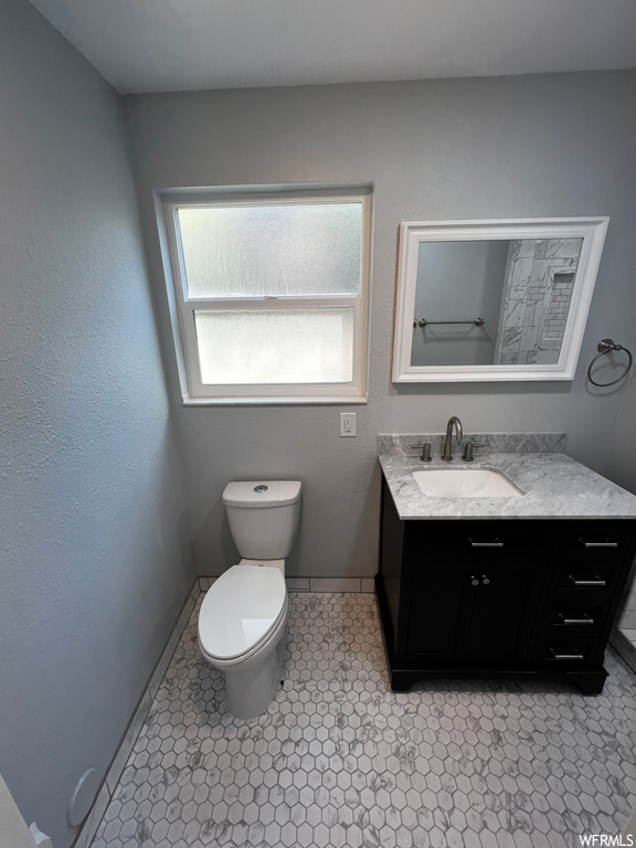 Bathroom featuring large vanity, toilet, plenty of natural light, and tile flooring