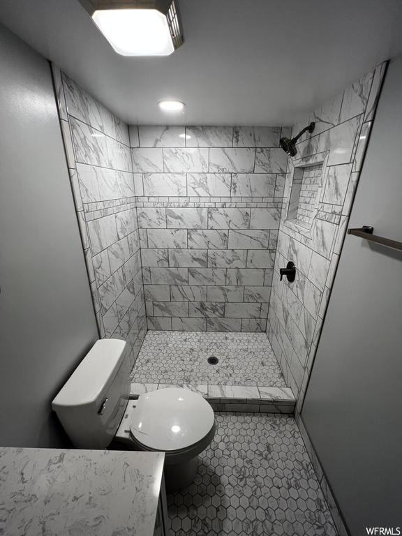 Bathroom featuring toilet, tile floors, and a tile shower