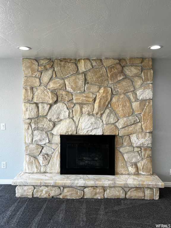 Details with a textured ceiling, carpet floors, and a stone fireplace