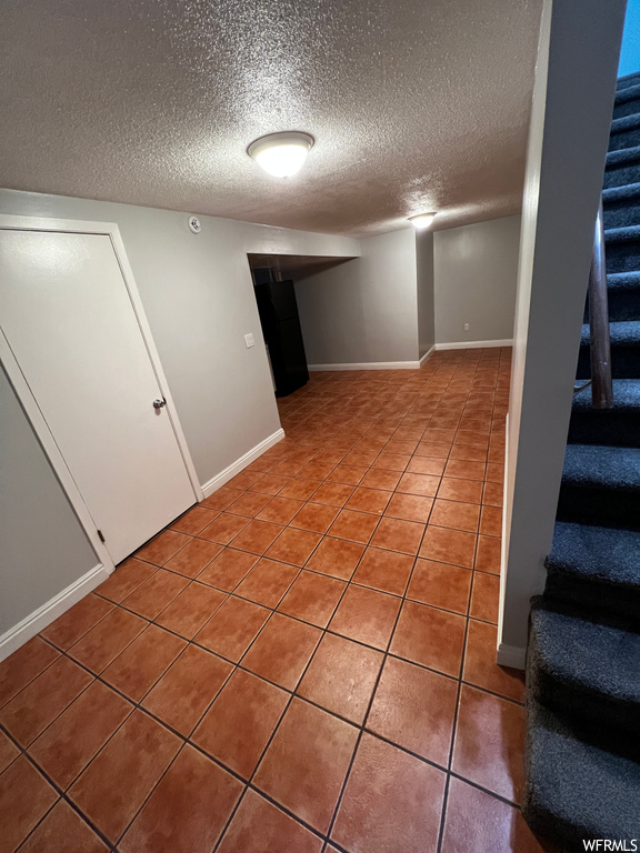 Basement with a textured ceiling and tile flooring