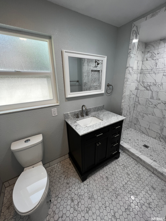 Bathroom with toilet, tile floors, large vanity, and tiled shower