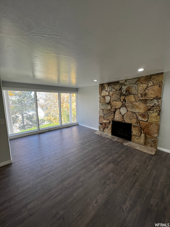 Unfurnished living room featuring dark wood-type flooring and a fireplace
