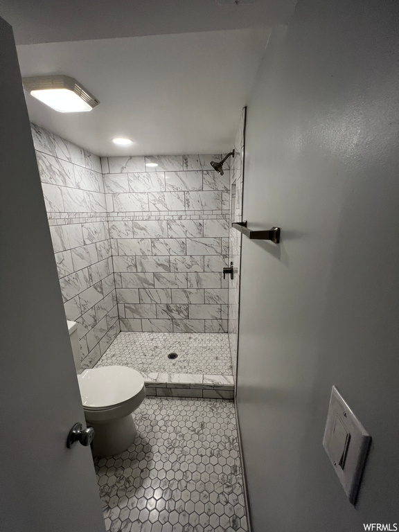 Bathroom with toilet, tile flooring, and tiled shower