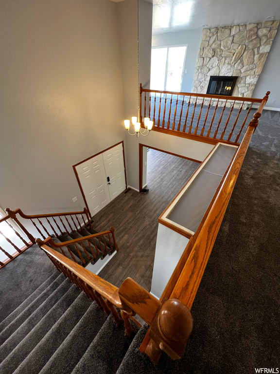 Stairs with a notable chandelier, dark hardwood / wood-style floors, and a fireplace