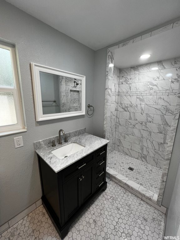 Bathroom with tiled shower, tile flooring, and vanity