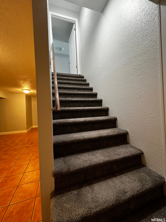 Stairway featuring light tile flooring