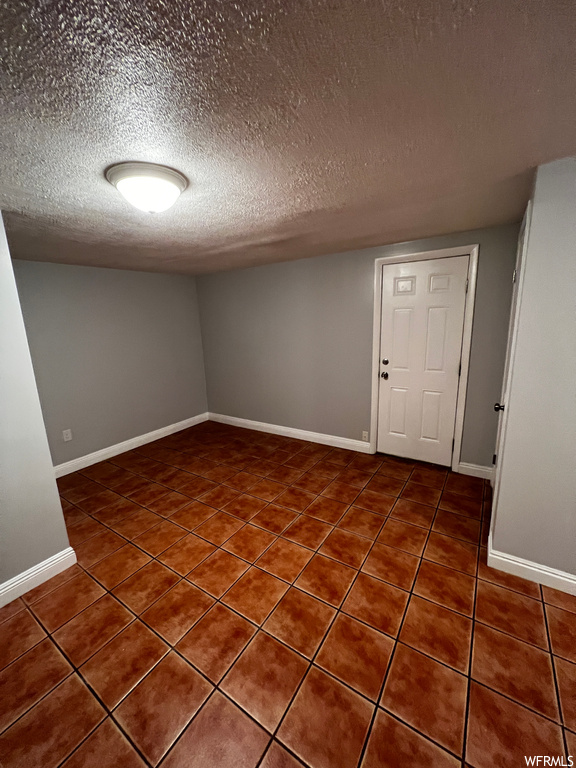 Spare room with dark tile flooring and a textured ceiling
