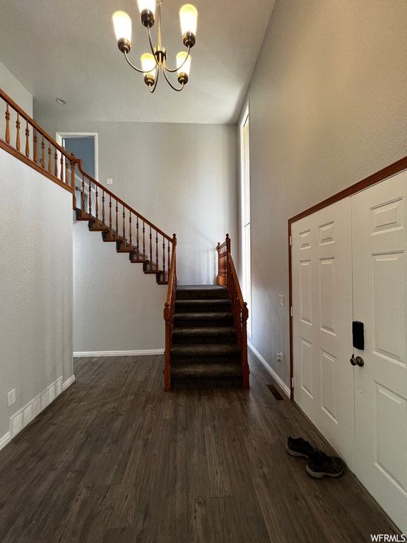 Staircase with dark hardwood / wood-style floors and a notable chandelier