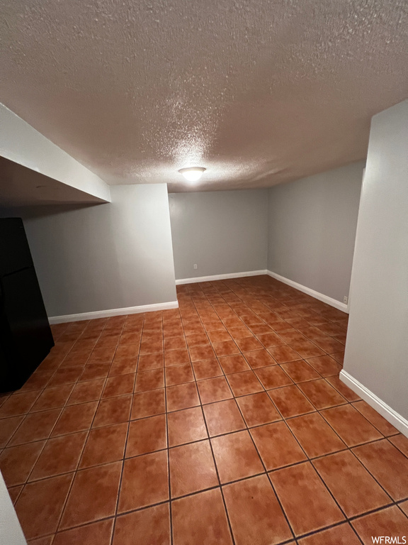 Basement with dark tile flooring and a textured ceiling