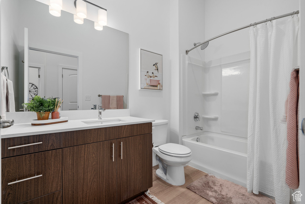 Full bathroom with shower / bath combo, wood-type flooring, oversized vanity, and toilet