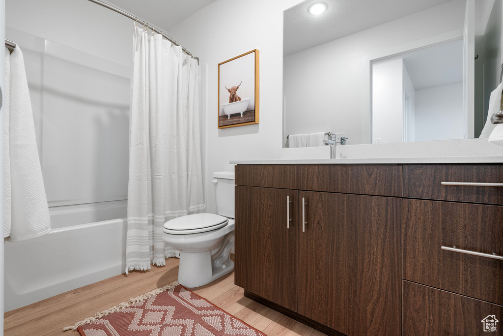 Full bathroom with vanity, hardwood / wood-style flooring, toilet, and shower / tub combo with curtain