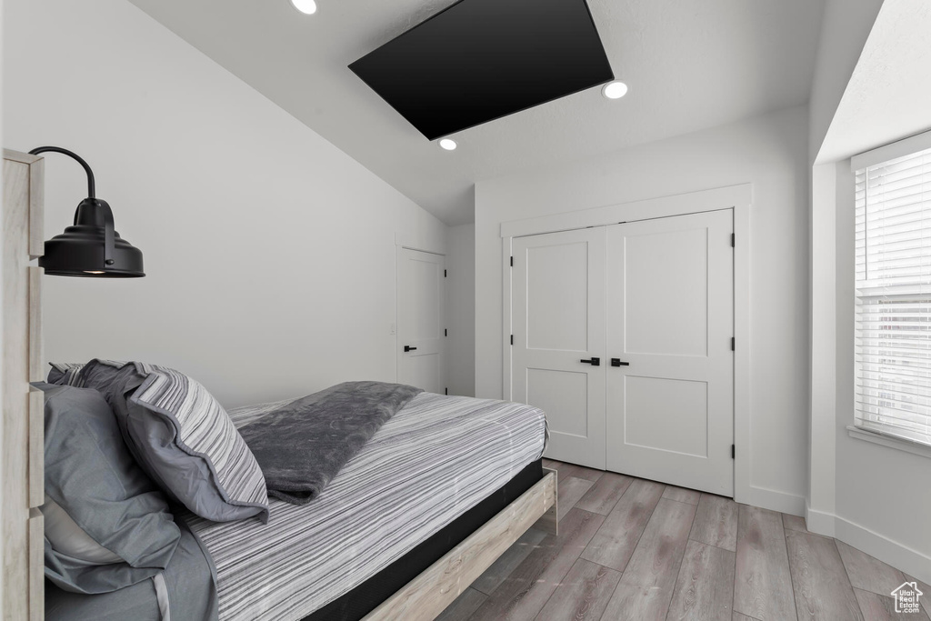 Bedroom featuring vaulted ceiling, a closet, and light hardwood / wood-style floors