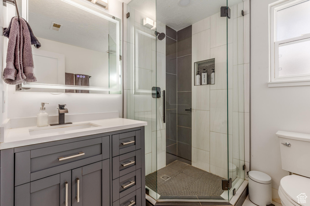 Bathroom with vanity, toilet, and a shower with shower door