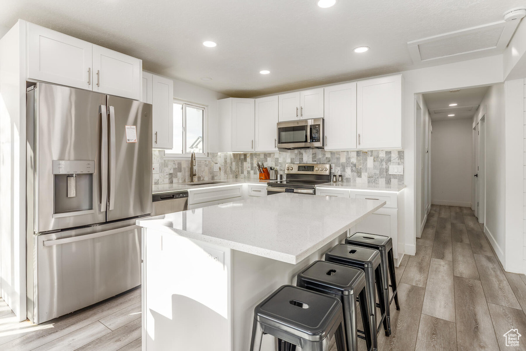 Kitchen featuring appliances with stainless steel finishes, a kitchen island, light wood-type flooring, and sink