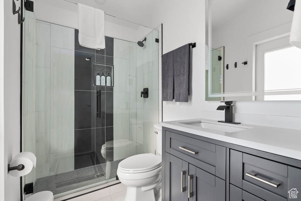 Bathroom featuring vanity, toilet, tile flooring, and a shower with door