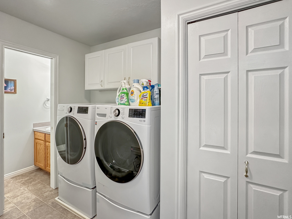 Laundry area with washer and dryer, cabinets, and light tile flooring