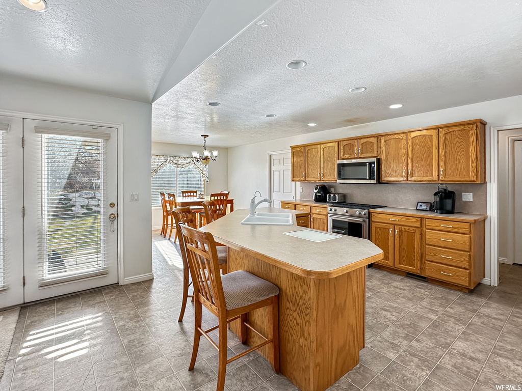 Kitchen featuring a chandelier, a healthy amount of sunlight, sink, and appliances with stainless steel finishes