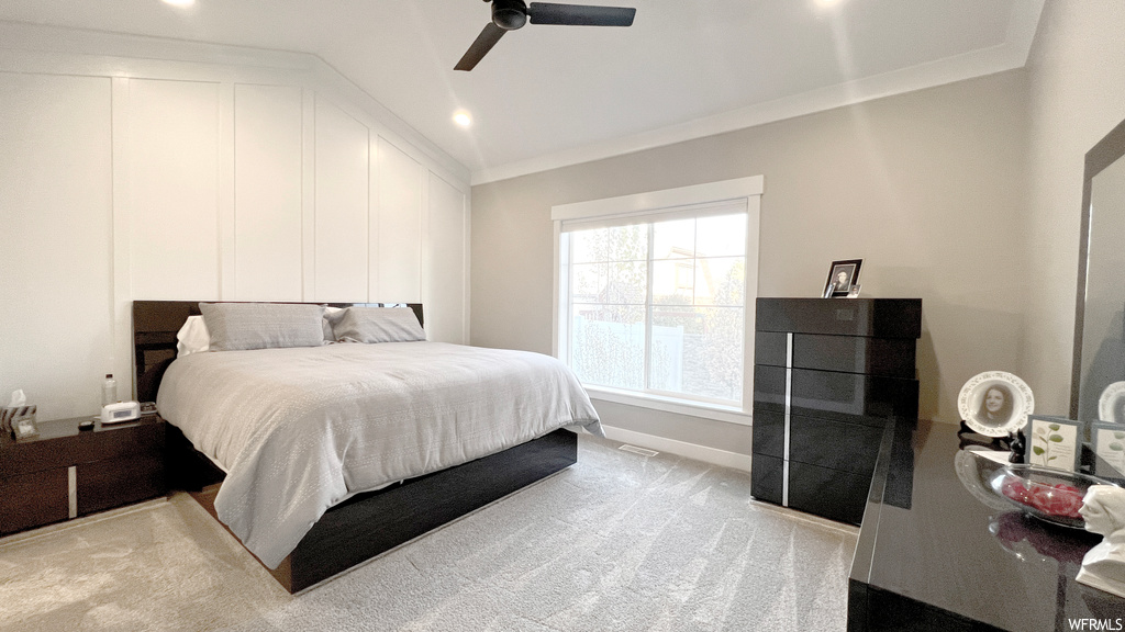 Carpeted bedroom with ceiling fan, ornamental molding, and vaulted ceiling