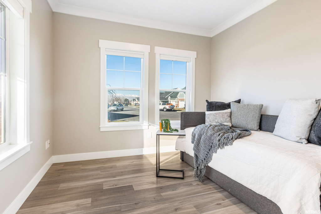 Bedroom with ornamental molding, light wood-type flooring, and multiple windows
