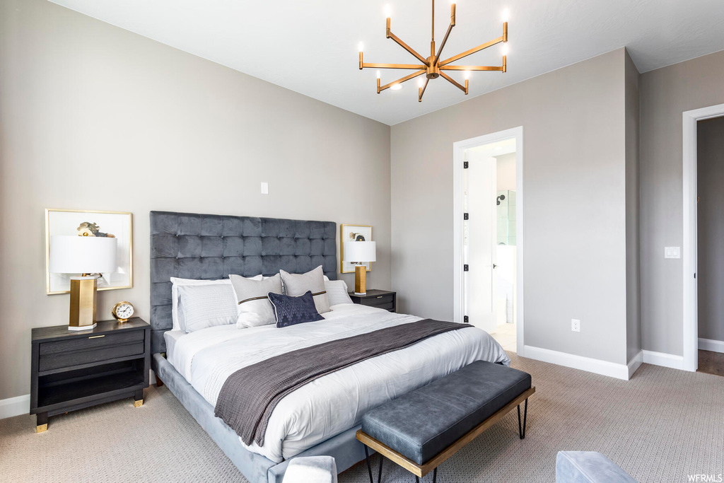 Bedroom with a notable chandelier, ensuite bathroom, and light colored carpet