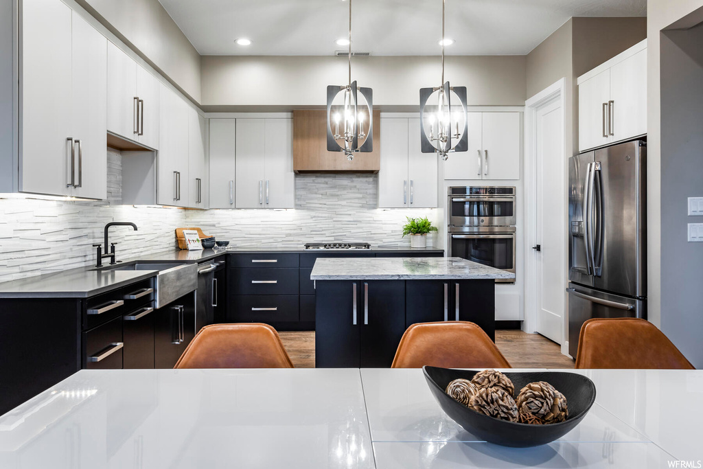 Kitchen featuring hanging light fixtures, a kitchen island, tasteful backsplash, and stainless steel appliances