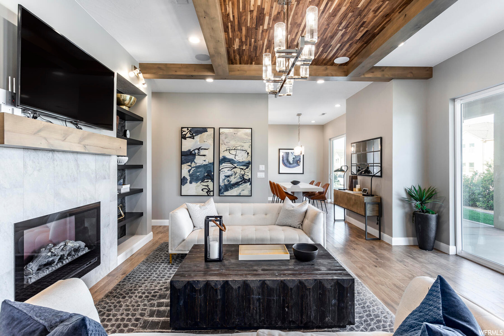 Living room featuring a tile fireplace, beam ceiling, dark hardwood / wood-style flooring, and wooden ceiling