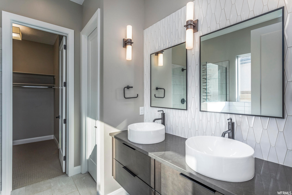 Bathroom featuring tile flooring, double sink vanity, tile walls, and backsplash