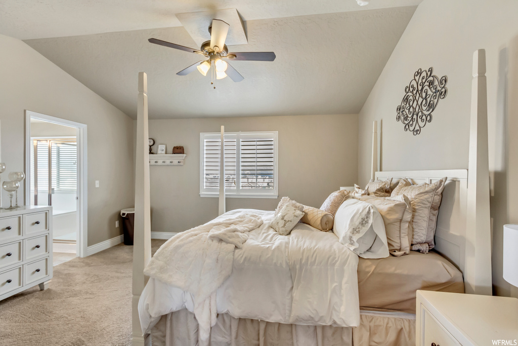 Bedroom with light colored carpet, ceiling fan, and vaulted ceiling