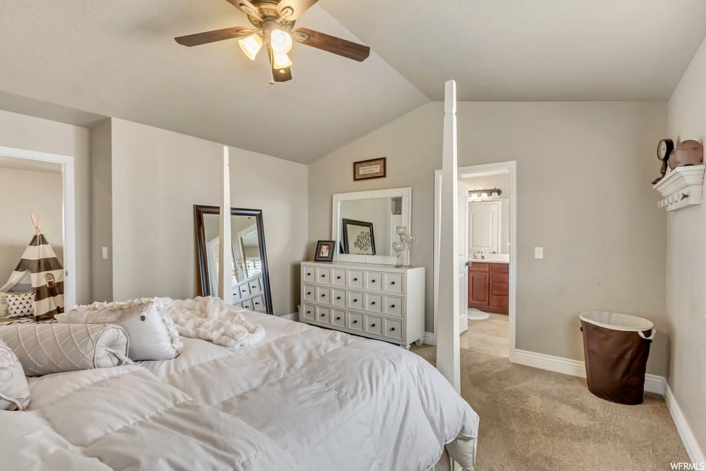 Carpeted bedroom featuring ceiling fan, ensuite bath, and vaulted ceiling