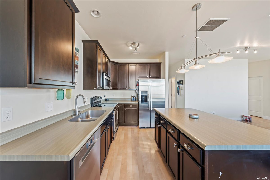 Kitchen featuring light hardwood / wood-style flooring, dark brown cabinets, pendant lighting, stainless steel appliances, and track lighting