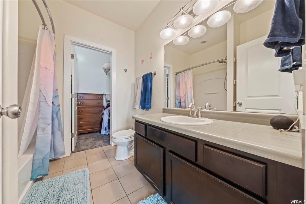 Full bathroom with shower / bath combo with shower curtain, tile flooring, toilet, and vanity