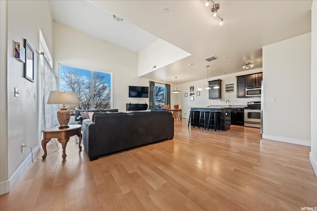 Living room featuring rail lighting, sink, and light hardwood / wood-style floors