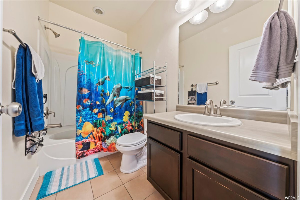 Full bathroom featuring shower / bathtub combination with curtain, toilet, tile floors, and vanity with extensive cabinet space