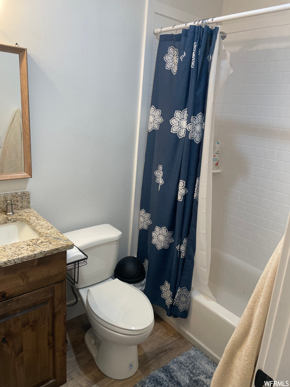 Full bathroom with shower / bath combination with curtain, vanity, toilet, and wood-type flooring