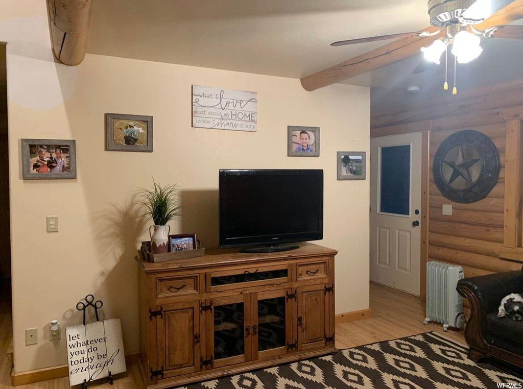 Living room with radiator heating unit, ceiling fan, and light hardwood / wood-style floors