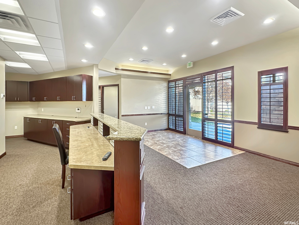 Kitchen with a center island, dark brown cabinets, and light carpet