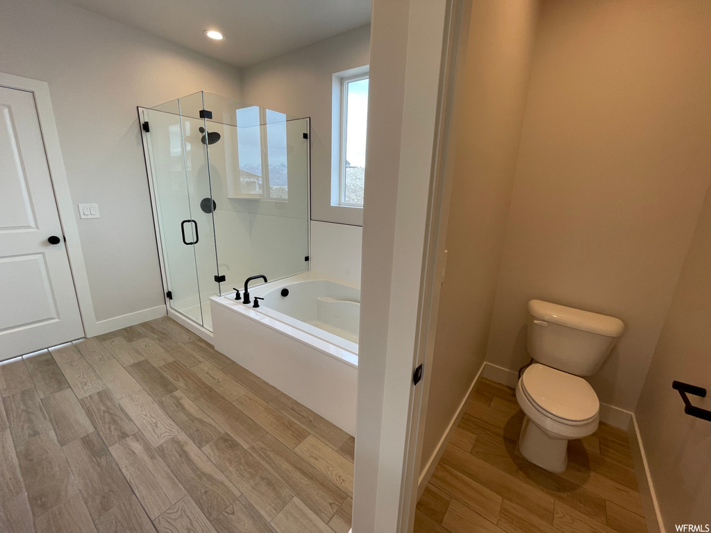 Bathroom featuring toilet, shower with separate bathtub, and hardwood / wood-style floors