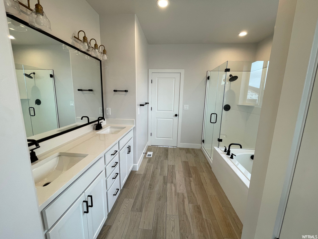 Bathroom featuring independent shower and bath, oversized vanity, double sink, and hardwood / wood-style flooring