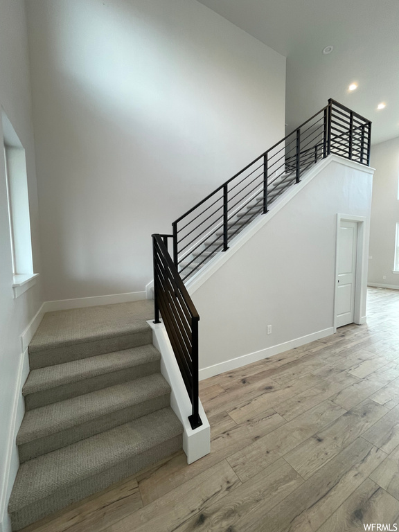 Stairs featuring a high ceiling and light hardwood / wood-style flooring