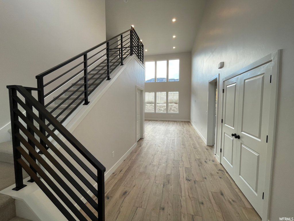 Staircase featuring a high ceiling and light hardwood / wood-style floors