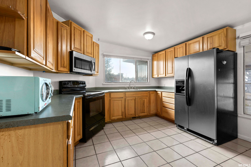 Kitchen with black appliances, sink, and light tile flooring