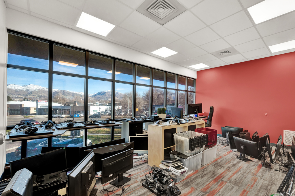 Office area with a paneled ceiling, light carpet, and a mountain view