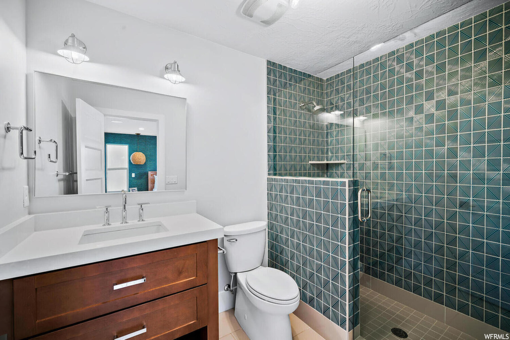 Bathroom featuring toilet, an enclosed shower, tile flooring, and vanity