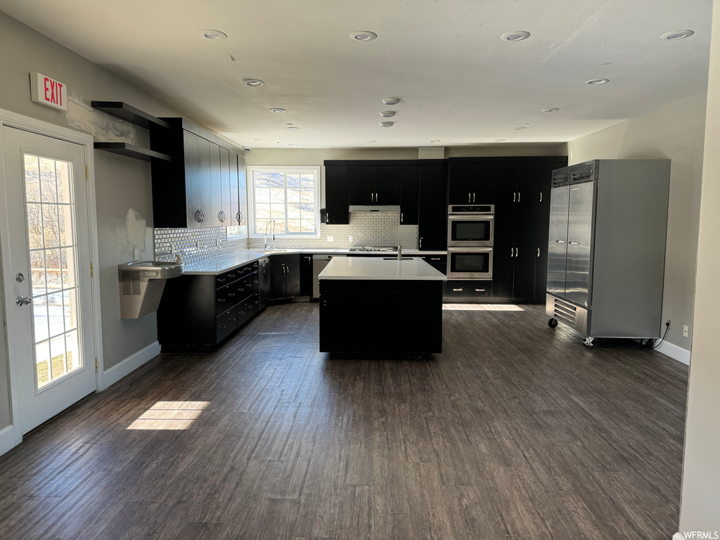 Kitchen featuring dark hardwood / wood-style floors, a center island, a healthy amount of sunlight, and double oven