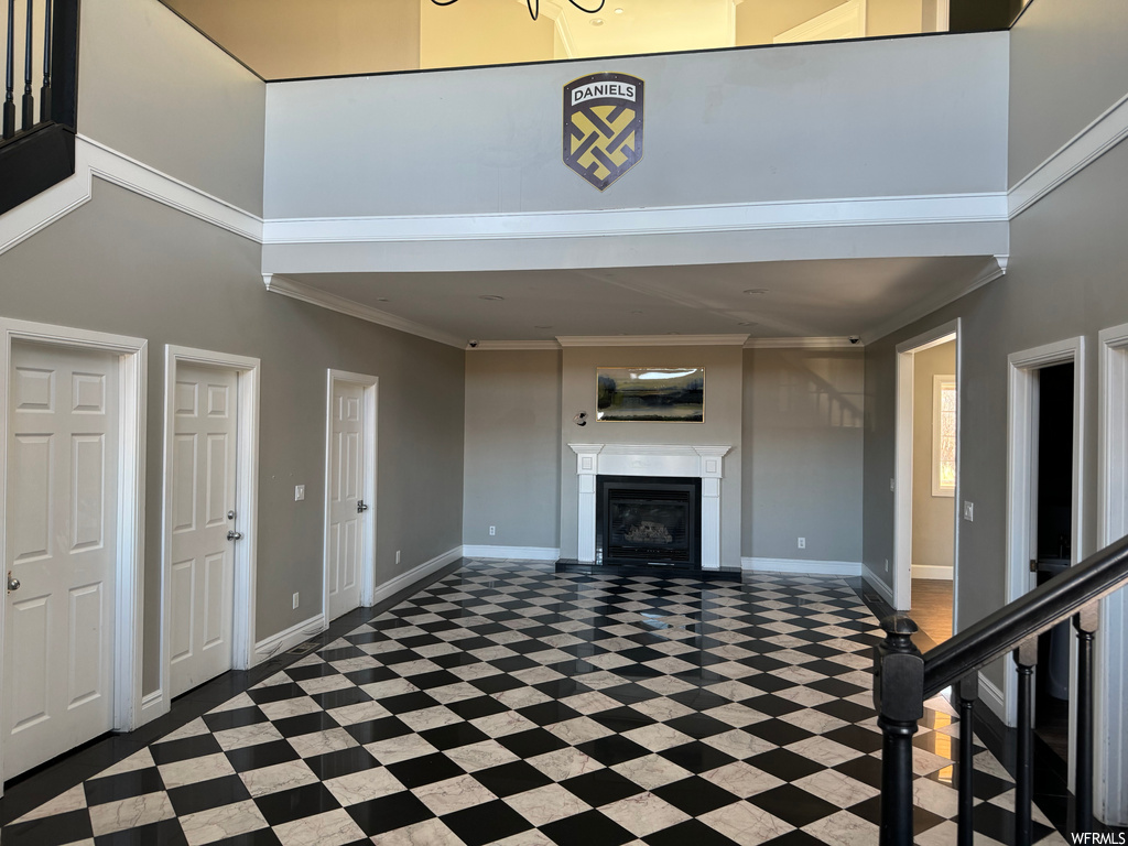 Foyer entrance with dark tile flooring, a towering ceiling, and ornamental molding